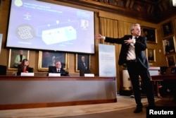 Член Нобелівського комітету Улоф Рамстрем (праворуч) пояснює принцип роботи елементу живлення. Ліворуч: його колега Сара Снуґеруп Лінсе та генеральний секретар Шведської королівської академії наук Йоран Ханссон