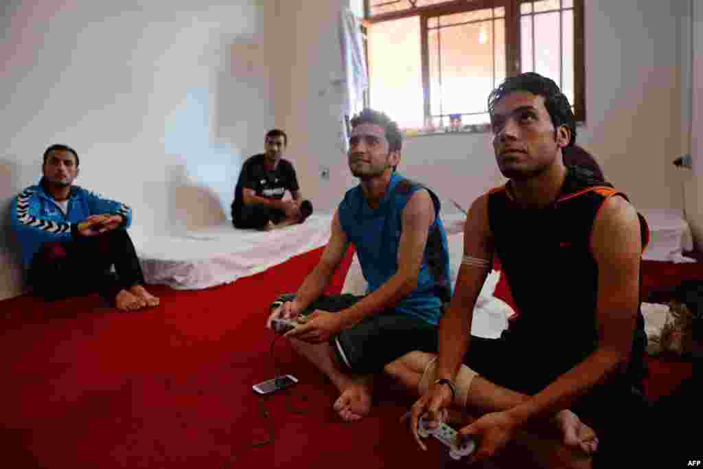 Afghan footballers play a video game in a dorm room while others watch at their communal house in Kabul.