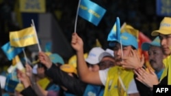 "Нұр Отан" партиясының жалауларын бұлғап тұрған адамдар.  