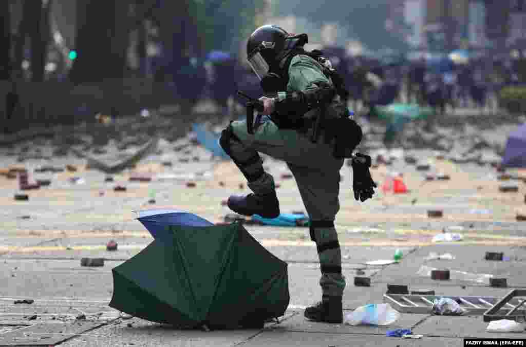 Спецназовец растаптывает зонтик, использованный продемократическим протестующим во время столкновения за пределами Гонконгского политехнического университета 18 ноября. (epa-EFE/Fazry Ismail)
