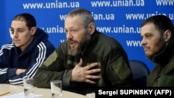 Киевдеги басма сөз жыйынында орусиялык аскер туткундары, полиция кызматкери (сол жакта) сержант Евгений Плотников,  полиция офицерлери подполковник Дмитрий Астахов жана капитан Евгений Спиридонов.  