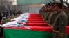 Afghan honor guards stand next to coffins as they pay tribute to soldiers who were killed in an Taliban attack in Kunar province.