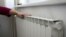Жылу радиаторын ұстап тұрған адам. (Көрнекі сурет)