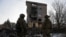 Ukrainian servicemen stand next to a residential building heavily damaged by a Russian military strike in Bakhmut. 
