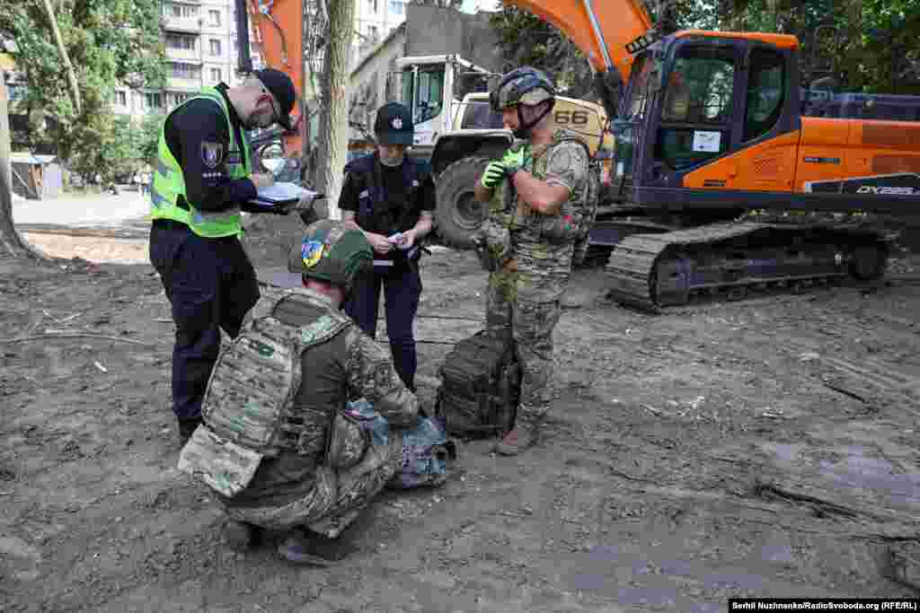Представники ДСНС та вибухотехніки оглядають чфрагмент ракети, яка влучила в будинок у Святошинському районі Києва