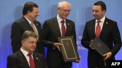 Ukrainanyň prezidenti Petro Poroşenko (öňdäki planda), ÝB Komissiýasynyň prezidenti Joze Manuel Barosso (arka planda), ÝB Geňeşiniň prezidenti Herman Wan Rompuý we Gürjüstanyň premýer-ministri Irakli Garibaşwili. Brýusel. 27-nji iýun, 2014 ý.