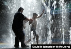 People cool off in a water fountain in Tbilisi.