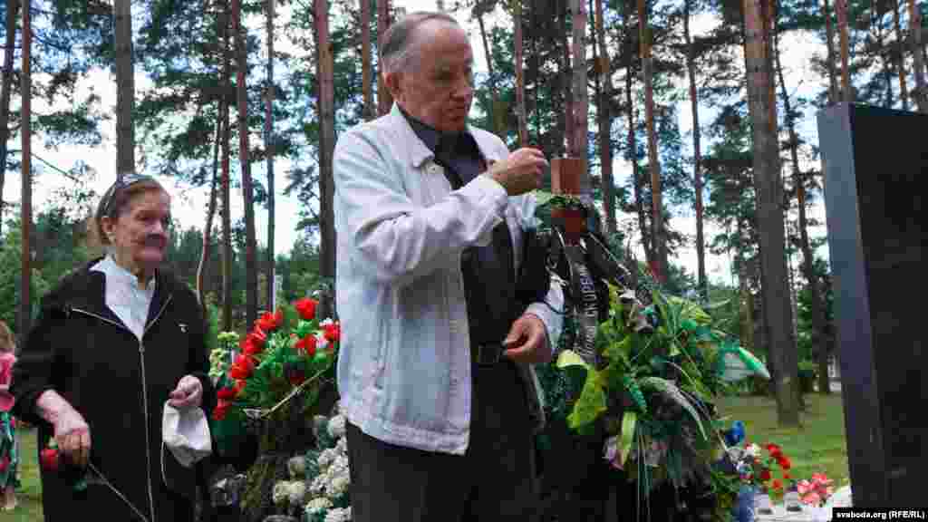 Ірына Быкава (л), Анатоль Вярцінскі хрысьціца ля магілы Васіля Быкава