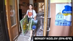 Місцева дівчина виносить картини з будинку культури в місті Чугуєві, який постраждав від обстрілу російських військових. Чугуїв, Харківська область, 25 липня 2022 року
