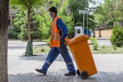 Работник коммунальных служб в защитной маске идет по улице. Алматы, 9 мая 2020 года.