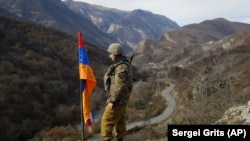 NAGORNO-KARABAKH -- An ethnic Armenian soldier stands guard next to Nagorno-Karabakh's flag atop of the hill near Charektar in at a new border with Kelbajar district turned over to Azerbaijan, November 25, 2020.
