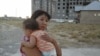 Айгуль Жайлаубаева, жительница микрорайона Нурсат, с ребенком на руках. Ее дом построен на участке, который власти считают "незаконно проданным". Шымкент, 11 августа 2014 года.