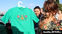 Печән базарында милли бизәкле күлмәк сайлаучы кыз