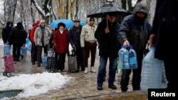  Local residents in Kyiv stand in line to fill up bottles with fresh drinking water. 