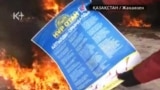 Человек в рабочей спецовке бросает в огонь предвыборный плакат президентской партии «Нур Отан». Жанаозен, 16 декабря 2011 года. Скриншот с видеосюжета телеканала "К-плюс".