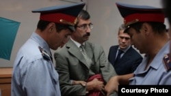 Сотрудники полиции защелкивают наручники на запястьях правозащитника Евгения Жовтиса в зале суда. Алматинская область, Баканас, 3 сентября 2009 года