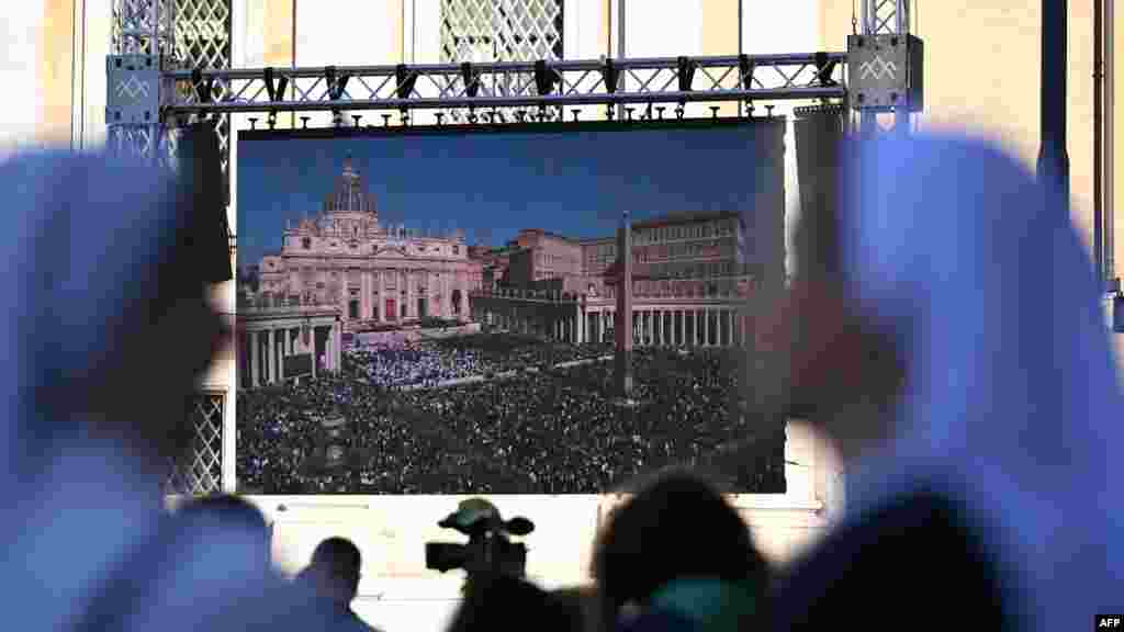 Манашкі глядзяць на гіганцкі экран, на якім адлюстроўваецца цырымонія пахаваньня папы Францішка, у цэнтры Рыму, 26 красавіка 2025 году