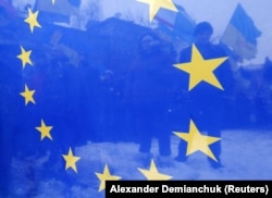 Сквозь флаг ЕС просматриваются протестующие во время Евромайдана в Киеве, переросшего в Революцию Достоинства. Киев, 17 декабря 2013 года