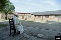 Погруженный в размышления Франциск перед бараками лагеря смерти Освенцим