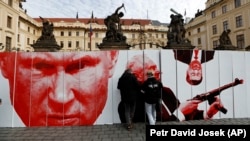Активисты возводят символическую стену с изображением президента России Владимира Путина, тогдашнего президента Чехии Милоша Земана и лидера КНР Си Цзиньпина перед Пражским Градом во время акции протеста 