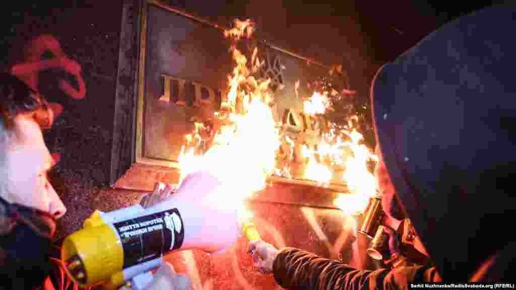 На фото: активісти підпалюють табличку на будівлі офісу президента України