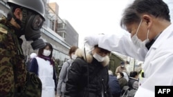 Дарыгер аскердин көзөмөлү астында аялдын радиация деңгээлин текшерүүдө. Фукусима перфекти, Нихонмацу шаары.