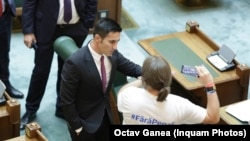 Senatorul PSD Claudiu Manda, în 3 iulie 2018 încearcă să îl convingă pe senatorul USR Mihai Goțiu să nu mai filmeze în timpul plenului Senatului. 