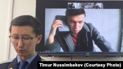 Темирлан Енсебек, автор Qaznews24 (на экране) и прокурор Дидар Кабаев (на переднем фоне). 9 апреля 2025 года