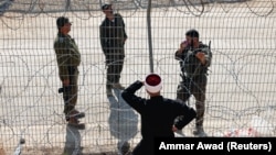 Сирийский друз разговаривает с израильскими солдатами через решетку и колючую проволоку на линии размежевания на Голанских высотах. Мадждаль-Шамс, 17 июля 2025 года