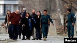 Afghan policemen evacuate foreigners from the site of an attack in Kabul on March 28.