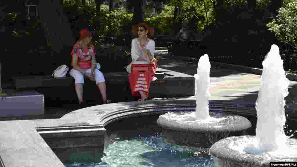 На бульварі біля фонтану сидять дами з віялами