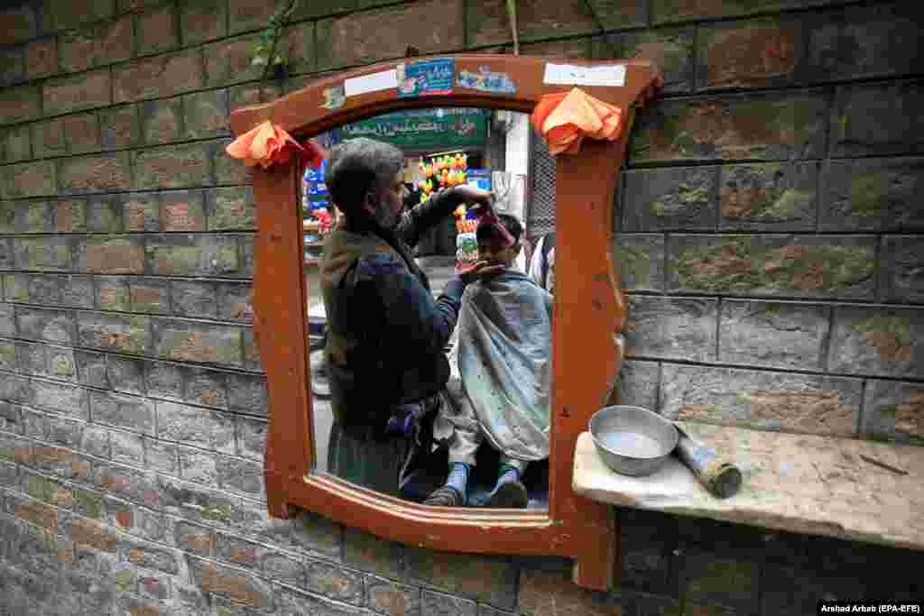 Перукар стриже клієнта в придорожній крамниці у Всесвітній день боротьби зі СНІДом, Пешавар, Пакистан, 1 грудня 2020 року. На думку лікарів, порізи лез, які не пройшли належну стерилізацію, є одними з основних причин поширення СНІДу. Всесвітній день боротьби зі СНІДом, який відзначають щороку 1 грудня, присвячений підвищенню обізнаності щодо поширення СНІД та ВІЛ-інфекцій.