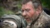 A Ukrainian soldier with a burned face is given first aid by medics on a road near Bakhmut on May 11.