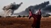 A woman reacts as smoke rises from the Syrian town of Kobani on October 13 after a strike from the U.S.-led coalition that is targeting the Islamic State militants besieging the town, seen from the Turkish-Syrian border.