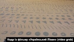 Знаки фінікійського алфавіту на стіні муніципалітету у місті Біблос (Ліван). Кадр із документального фільму «Український Ліван» (оператор – Михайло Шелест)