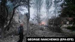 Bir adam 21-nji iýulda Kramatorsk şäherine edilen rus raketa hüjüminden soň, zyýan çeken mekdebiň öňünden geçip barýar. 