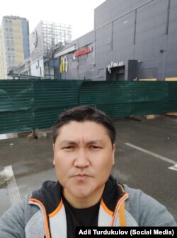 Адиль Турдукулов на фоне пострадавшего от ракетного удара торгового центра. Киев, Украина.