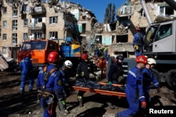 Спасатели несут тело человека, вытащенного из-под обломков здания, Киев, Украина, 28 августа 2025 года