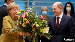 Повноваження Анґели Меркель офіційно вже припинилися, проте вона продовжує виконувати свої обов’язки до того, як буде сформовано новий уряд під керівництвом Олафа Шольца (праворуч на фото)