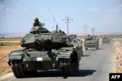 Turkish troops driving tanks on one of their country's military incursions into Syria earlier this year.