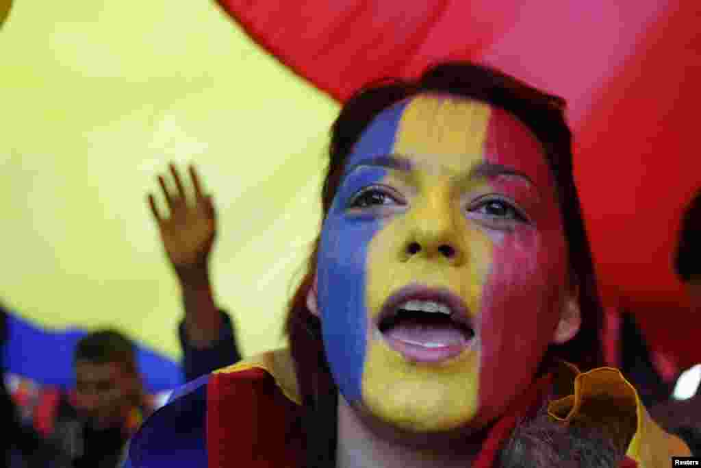 Лицо женщины выкрашено в цвета румынского флага во время демонстрации в центре Бухареста. Ее участники призвали начать процесс объединения Румынии и Молдавии. 