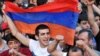A demonstrator holds an Armenian flag as others shout slogans during a protest against an increase on electricity prices in Yerevan on June 25.