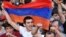 A demonstrator holds an Armenian flag as others shout slogans during a protest against an increase on electricity prices in Yerevan on June 25.