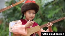 Музыкалык мектептин ачылыш салтанатында күү черткен кыз. 