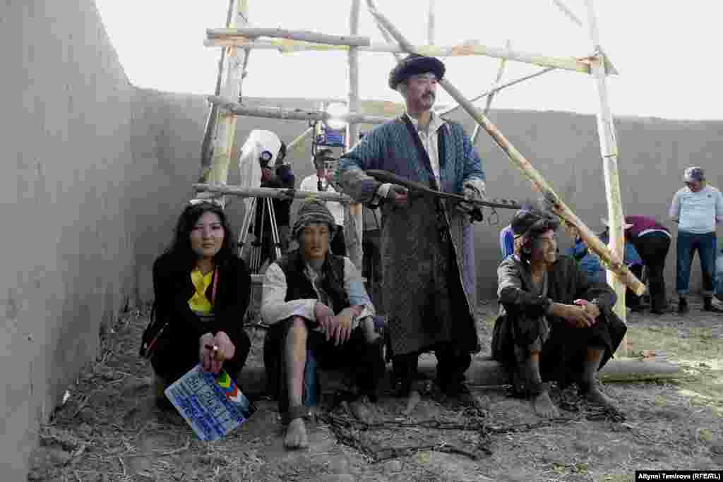 Атайын фильм үчүн курулган чептин дубалдарынын ичи. Артисттер эс алып көлөкөдө отурушат.