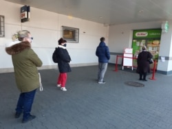 Чехтер дарыкананын алдында бири-биринен алыс аралыкта кезекте турушат. Прага. 24.3.2020.