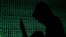 ILLUSTRATION -- FILE PHOTO: A hooded man holds a laptop computer as cyber code is projected on him in this illustration picture taken on May 13, 2017. 