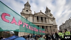 Британия. Өкмөттүн экономикалык саясатына жана килейген корпорациялардын суктугуна каршы уюшкан кыймыл мүчөлөрүнүн Лондон фондулук биржасынын бет маңдайында тиккен чатырлары. Баннерде "Капитализм кризисте" деген сөз жазылган. 16-октябрь 2011