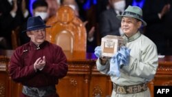 Монголиянын мурдагы президенти Халтмаагийн Баттулга жаңы шайланган президент Ухнаагийн Хурэлсухко бийликти тапшырып берүүдө.  25-июнь, 2021-жыл.