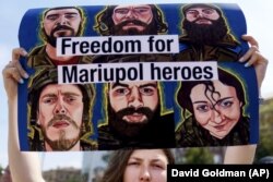 Вікторія Думич, чоловік якої служить у війську, тримає плакат на підтримку українських військових із полку «Азов»